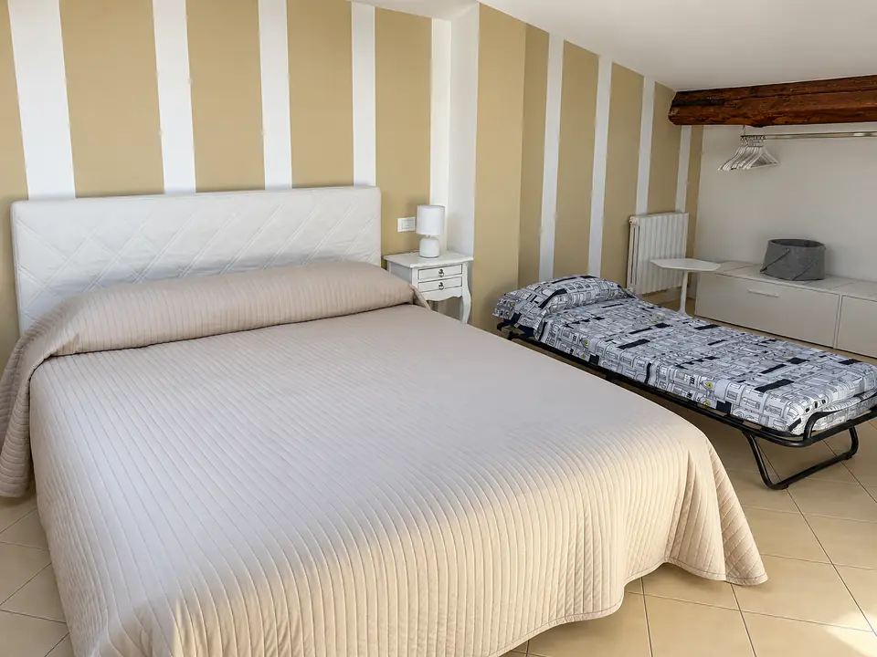 Letto matrimoniale e letto singolo nella stessa camera, con l’appendiabiti sotto la trave